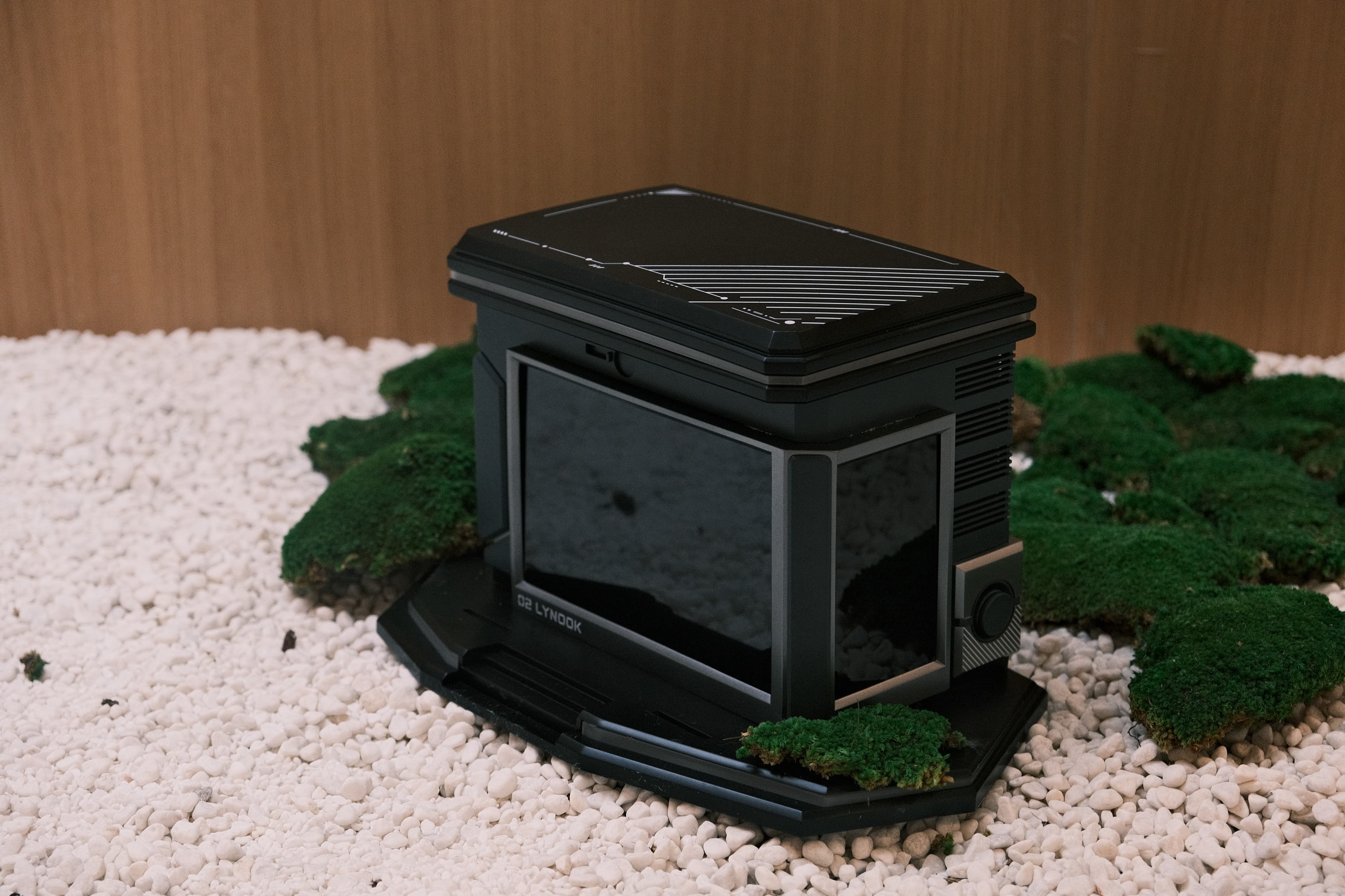 Black LYNOOK physical prototype photographed among moss and white stone